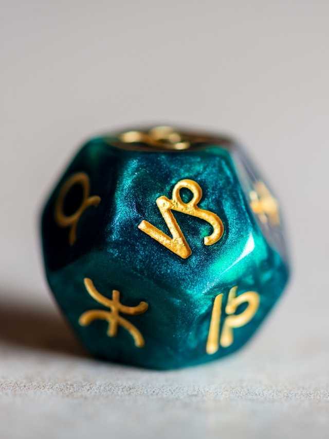 A green and gold dice with zodiac symbols on it.