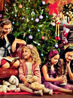 A group of girls celebrating Christmas Eve in front of a beautifully decorated Christmas tree.