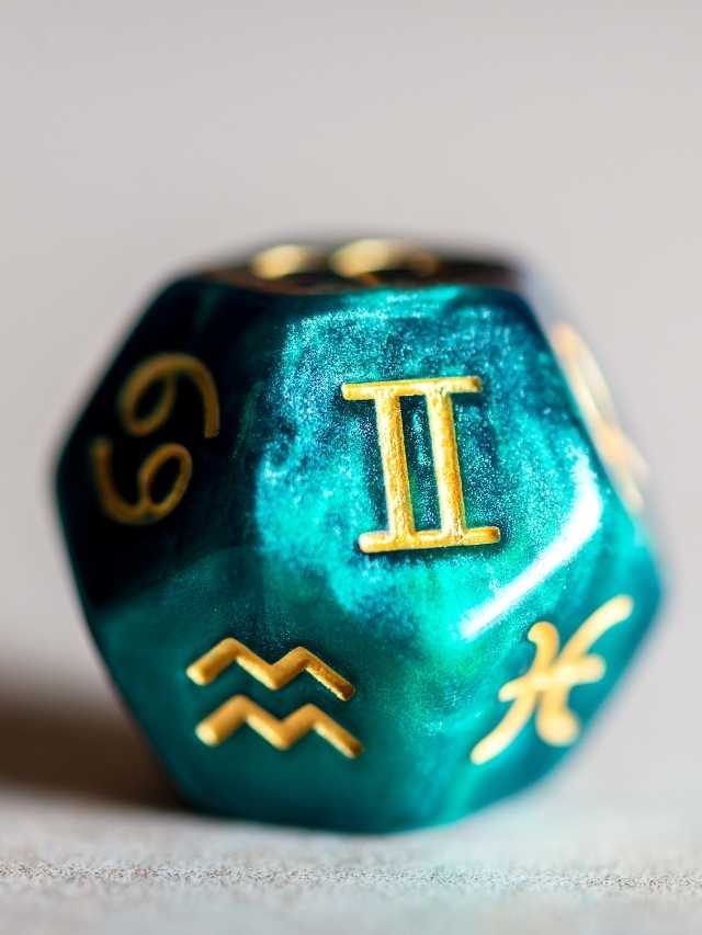 A green and gold dice with zodiac symbols on it.