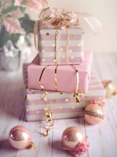 Pink and gold Christmas gifts for girls displayed on a wooden table.