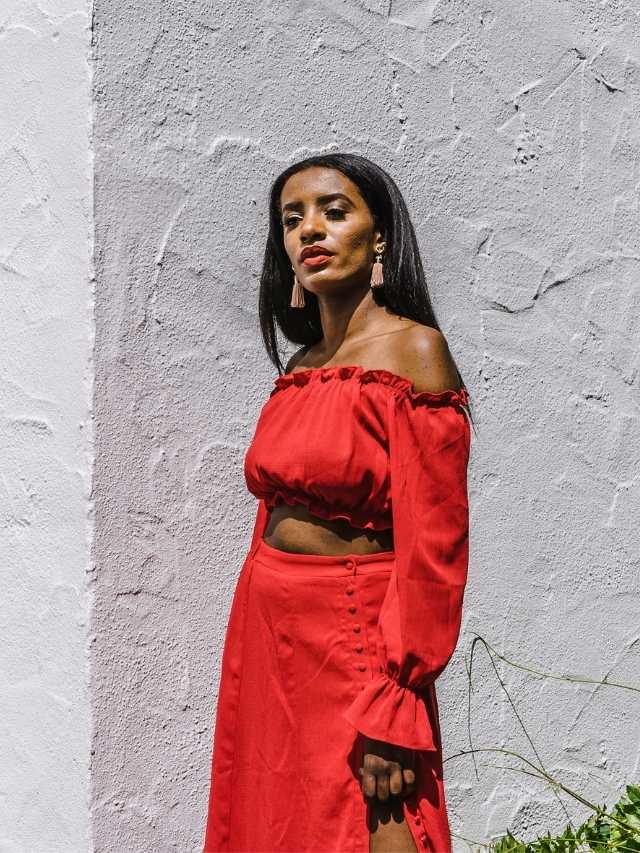 A woman wearing a red off the shoulder top and skirt.