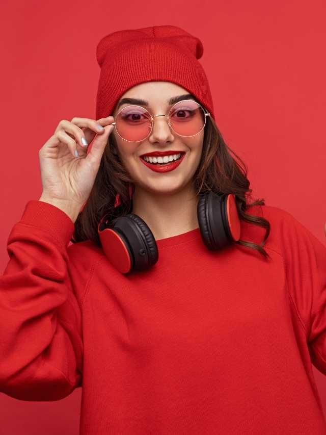 A woman in a red sweater wearing headphones and a beanie.