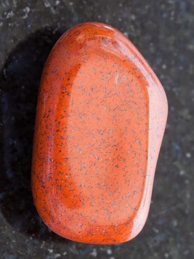 An orange stone sitting on a black surface.