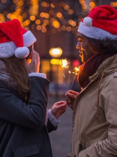 Two people in santa hats holding sparklers for student gift ideas for Christmas.