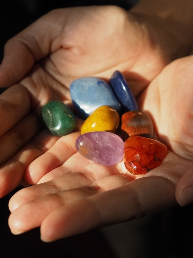 A person's hands holding a variety of colored stones.