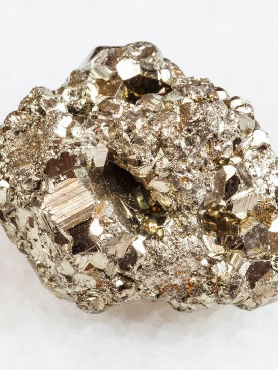 A piece of gold and silver mineral on a white surface.