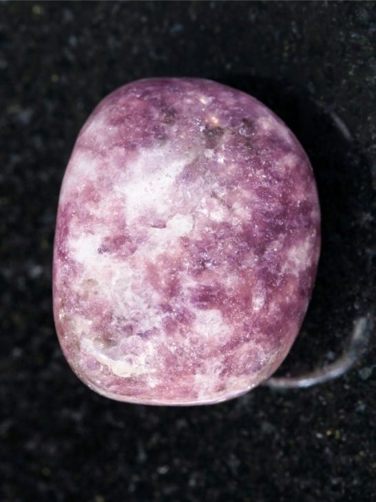 A purple stone sitting on a black surface.