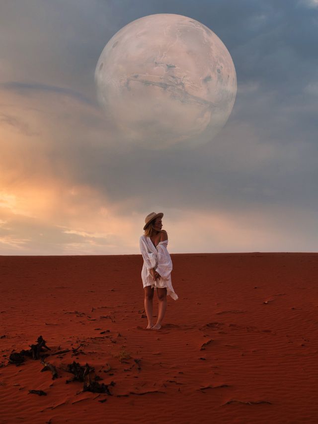 A woman standing in the desert with a full moon in the background, reflecting on the angelic significance of number 303.