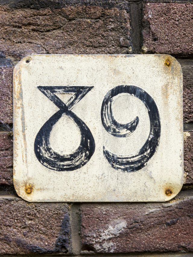 A house number sign on a brick wall with angel number 89 meaning.