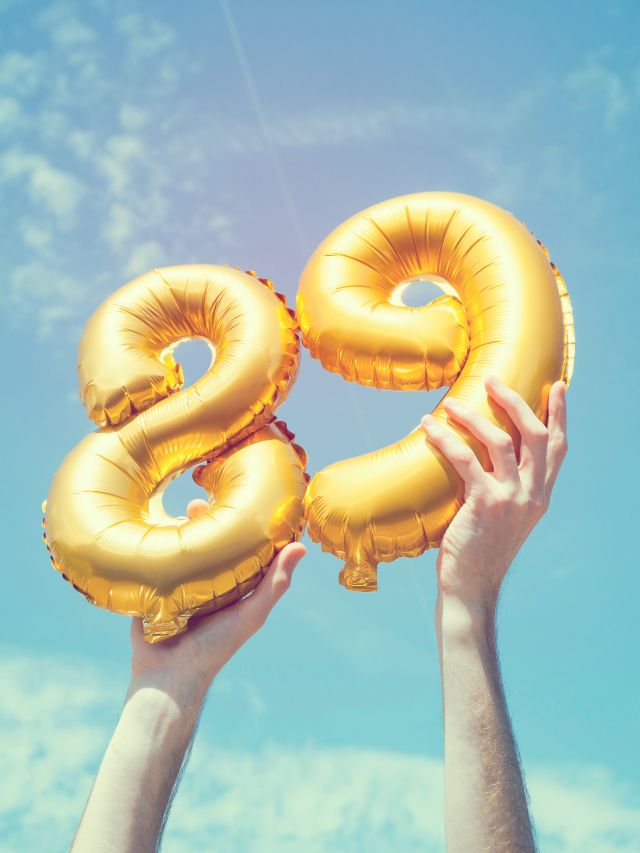 Two hands holding gold balloons shaped as the number 29 with angel number 89 meaning.