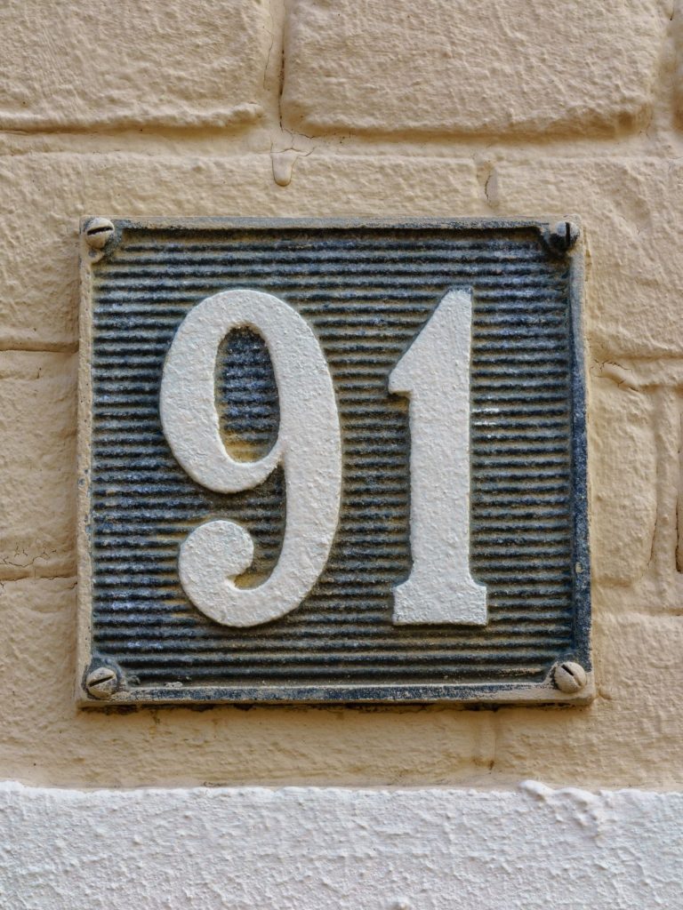 A house number sign on a brick wall with spiritual meaning.
