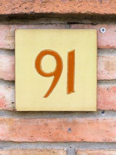 An angelic house number on a brick wall.