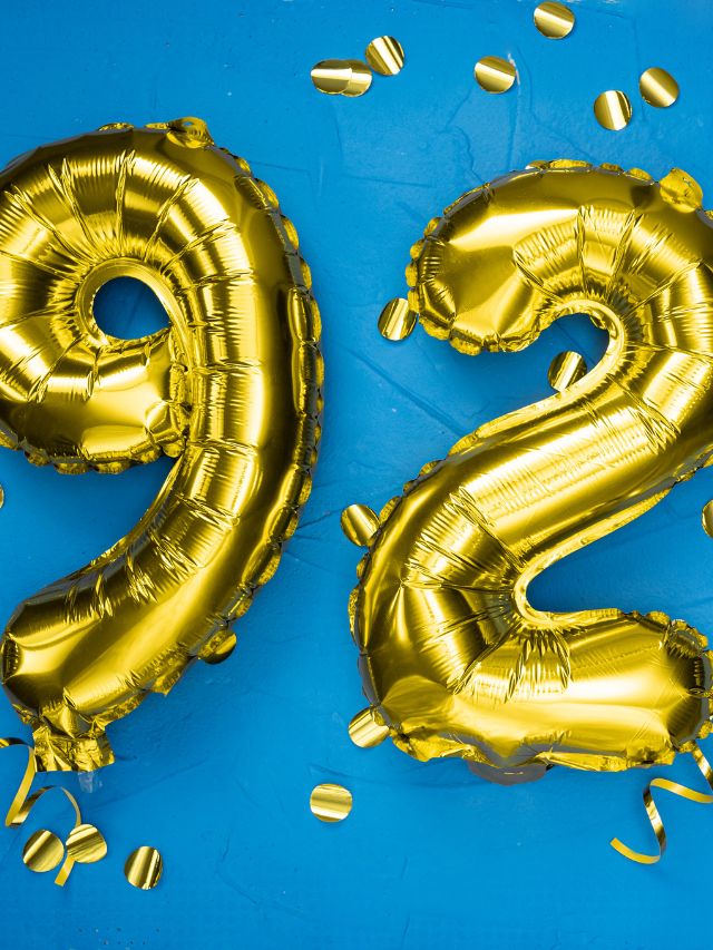 Gold foil balloons forming the number 92 on a blue background signify angelic significance.
