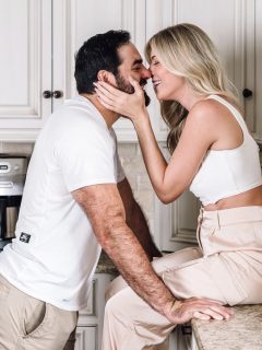A man and woman passionately kissing in a kitchen.