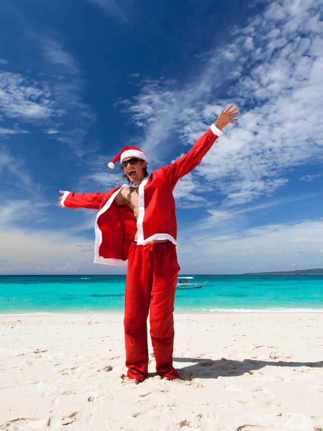A man dressed as santa claus on the beach.