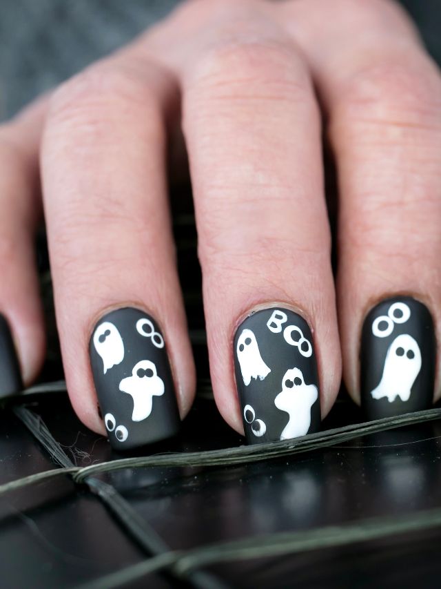 A person holding a black nail with white ghosts on it.