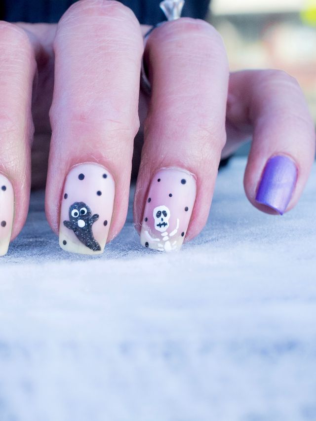 A woman's nails are decorated with skulls and polka dots.