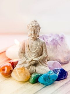A buddha statue surrounded by colorful stones and a candle.