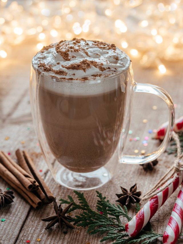 A cup of hot cocoa with cinnamon sticks and candy canes.