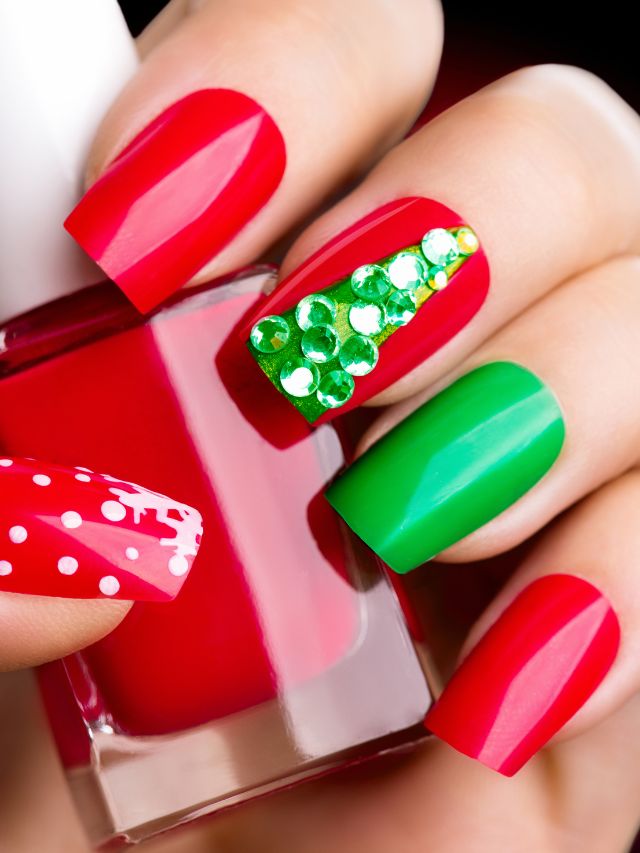 A woman is holding red and green nail polish with a christmas tree on it.