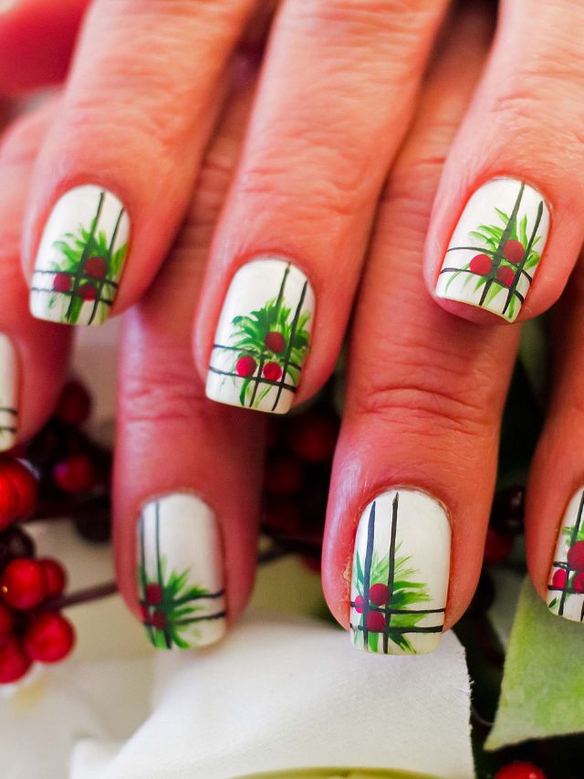 A woman's nails are decorated with holly leaves and berries.