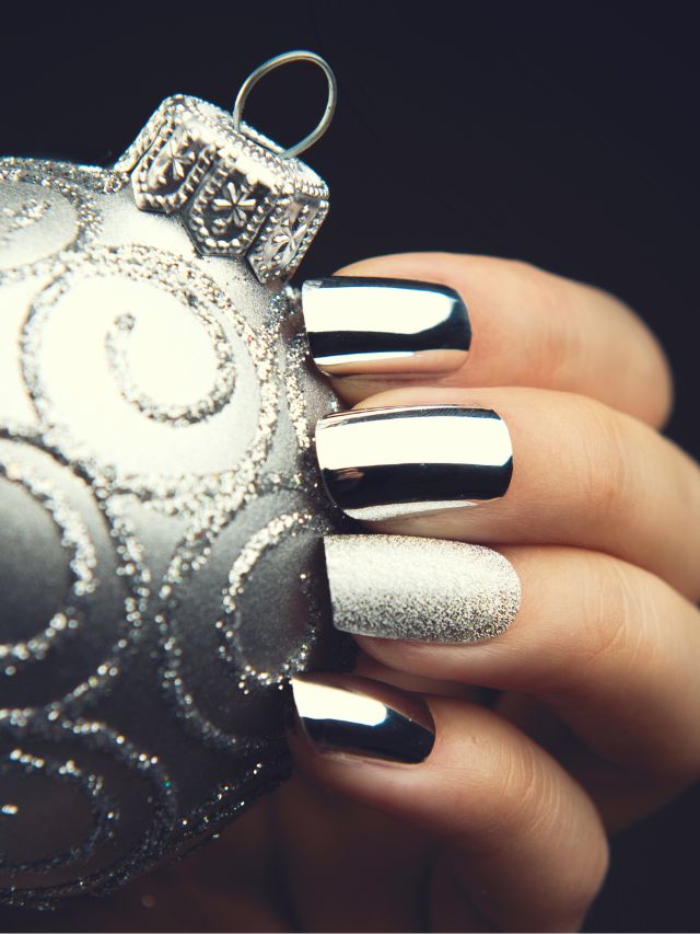 A woman's hand holding a silver christmas ornament.
