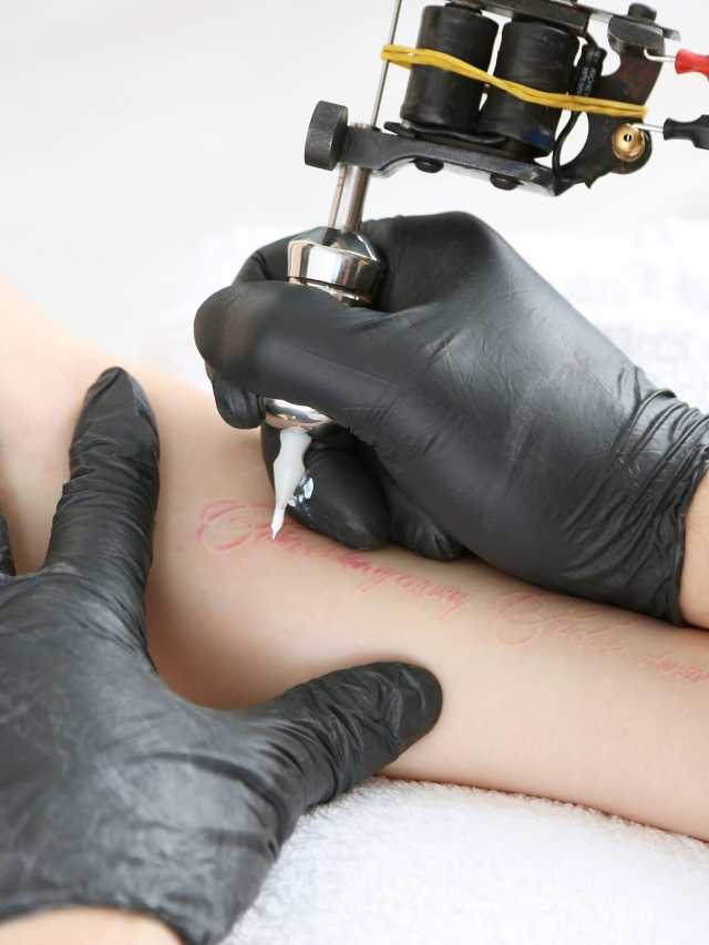 A woman getting a tattoo with a tattoo machine.