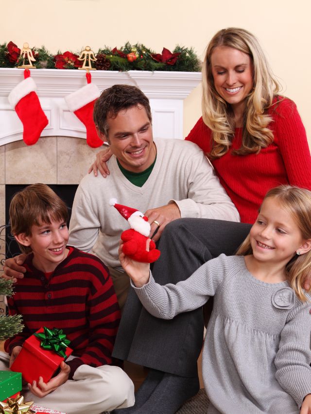 A family sitting on the floor next to a christmas tree.