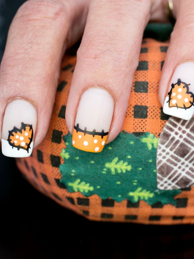 A woman's nails are decorated with pumpkins and leaves.