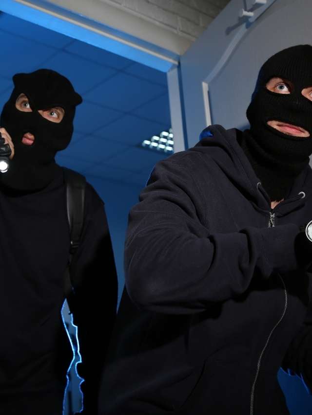 Two robbers in masks holding flashlights.