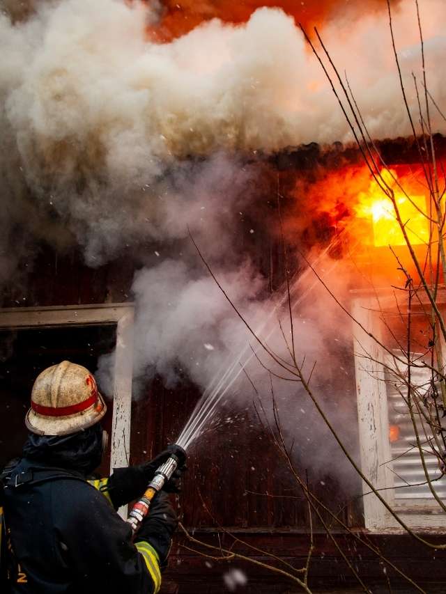 A firefighter is putting out a fire in a house.