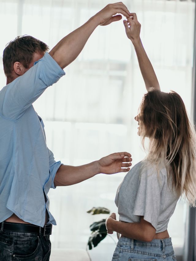 A man and woman dancing in a living room.