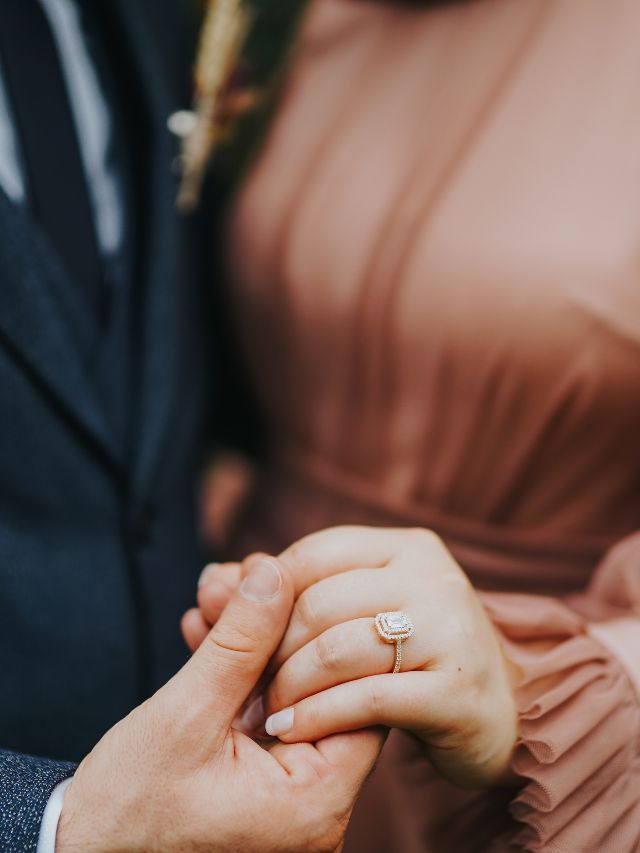 A bride and groom holding their wedding rings.