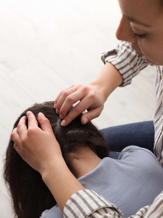 A woman is putting a woman's hair on her head.