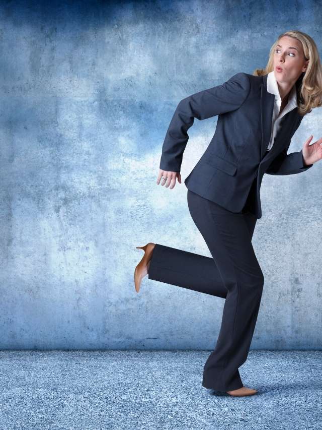 A business woman running away from a wall.