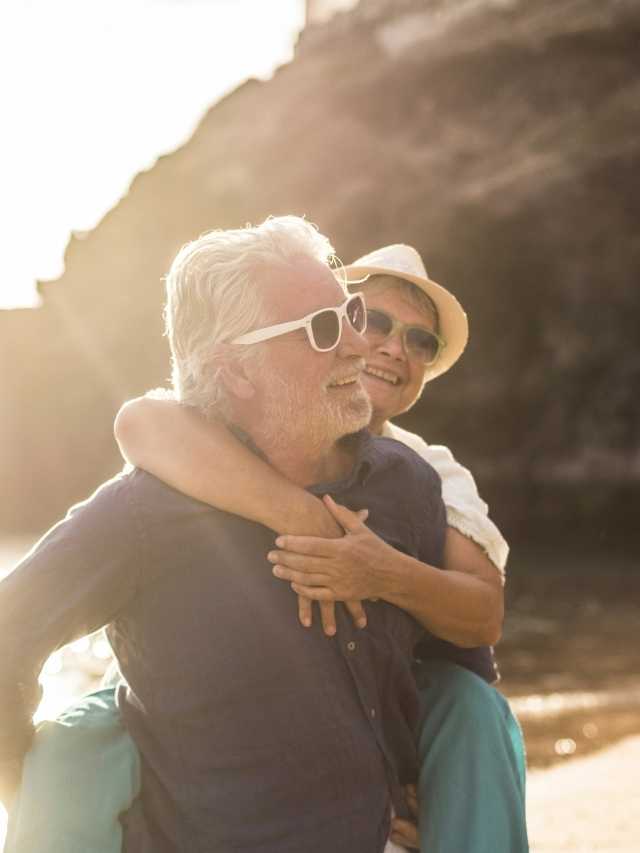An older couple hugging each other on the beach.