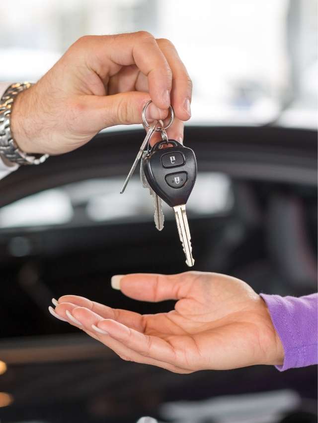A woman handing a car key to another person.