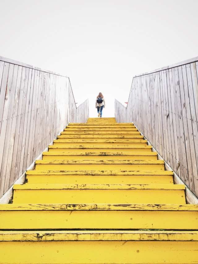 A person is walking up a yellow stairway.