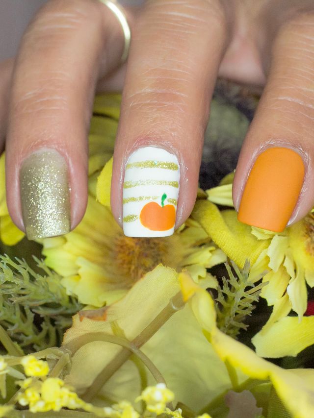 A woman's nails are decorated with pumpkins and sunflowers.