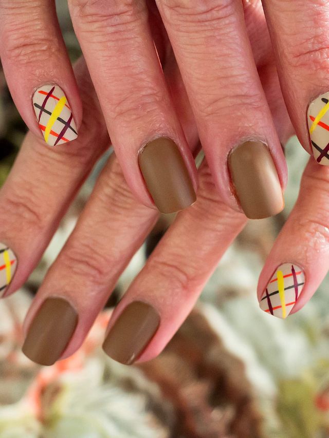 A woman's nails are decorated with a plaid pattern.