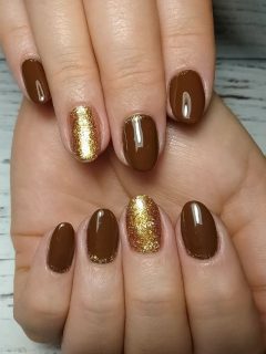 A woman's hands with brown and gold nails.