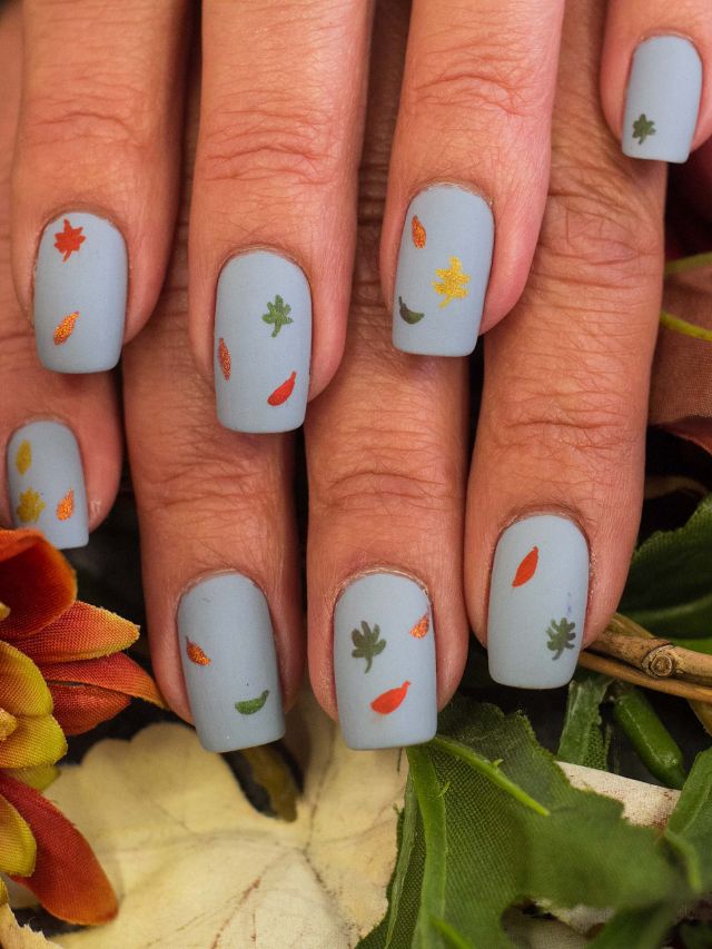 A woman's nails with fall leaves on them.