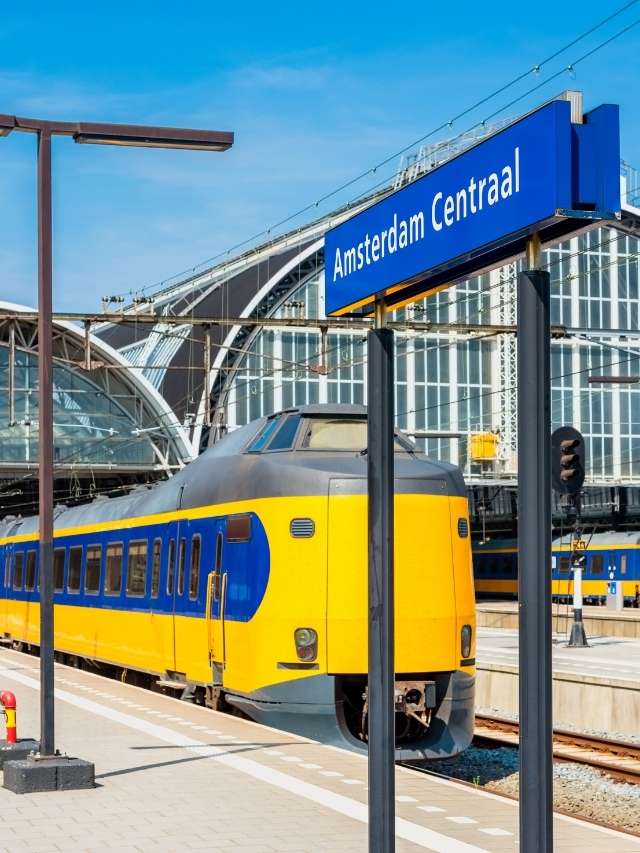 A yellow and blue train is parked at a train station.