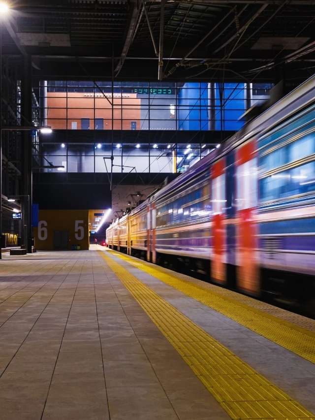 A train is pulling into a station at night.