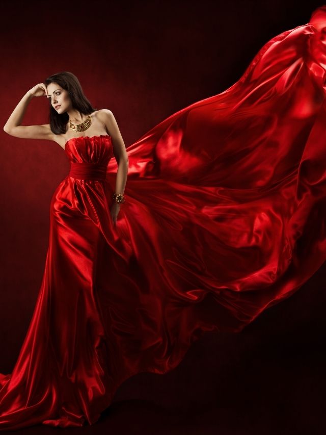 A woman in a red dress posing on a black background.