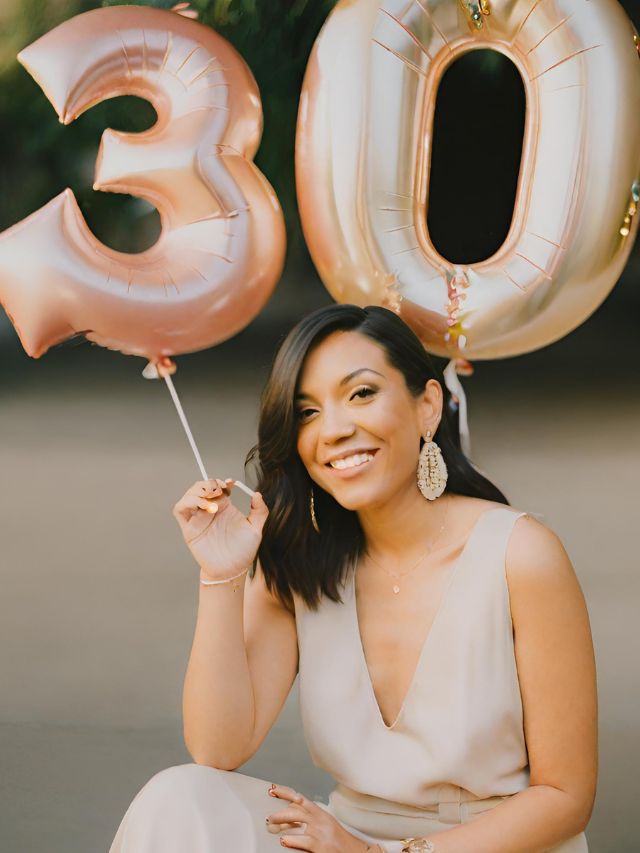 A woman holding a 30th birthday balloon.