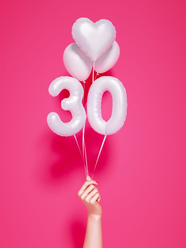 A woman's hand holding balloons with the number 30 on a pink background.