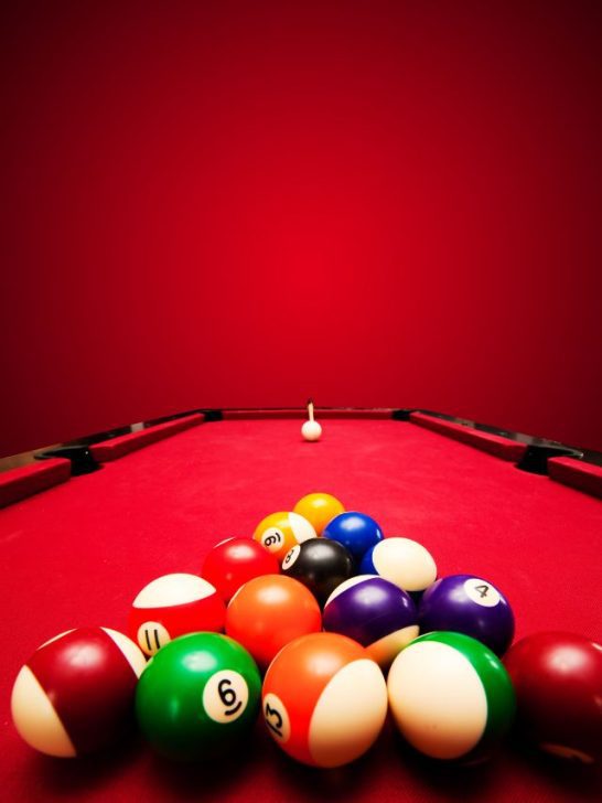 A billiard table with pool balls in front of a red background.