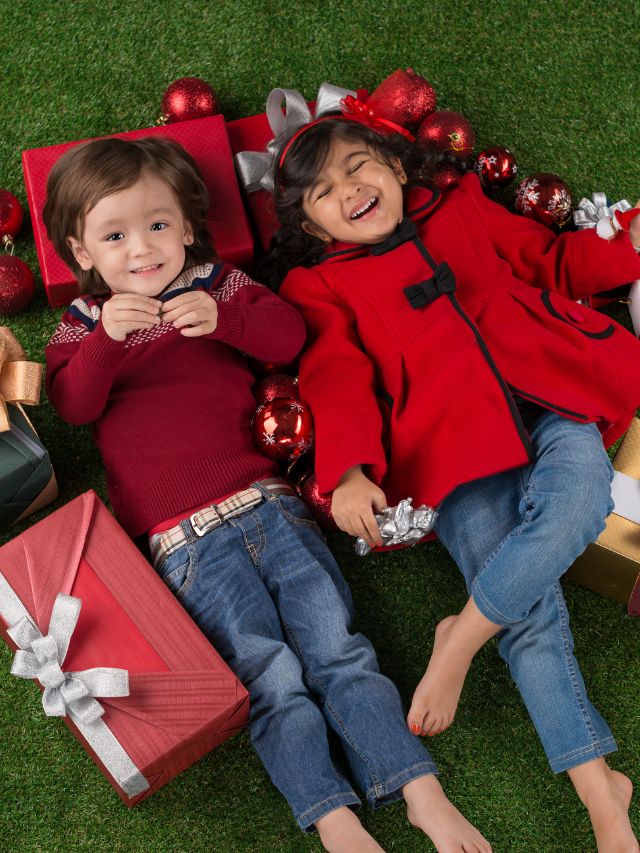 Two children enjoying their Christmas presents while lying on the grass.