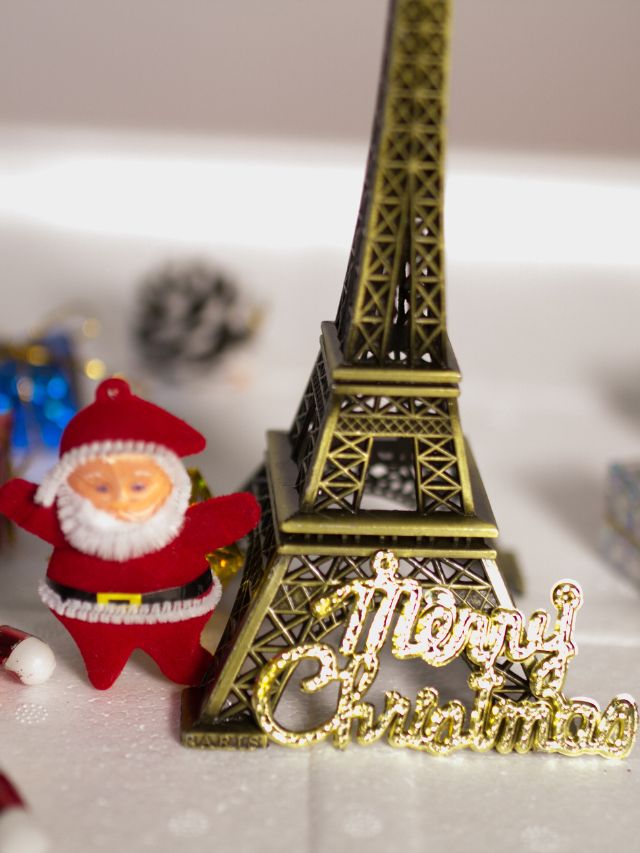 A santa claus figurine stands next to the eiffel tower in paris christmas party theme